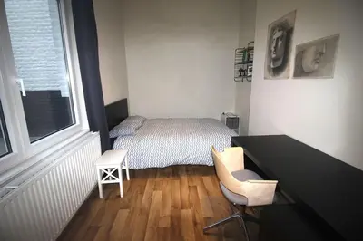 a bedroom with a bed and a desk and a window at Bel appartement 2 chambres avec terrasse in Liège
