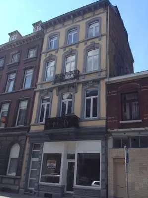 a tall brick building with windows on a street at Joli appartement 2 chambres à Liège in Liège