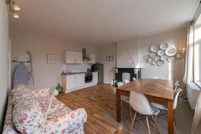 a living room with a table and a couch and a kitchen at Appartement 4 chambres à Liège in Liège