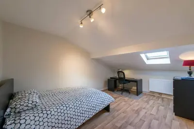 a bedroom with a bed and a desk and a window at Appartement 4 chambres à Liège in Liège