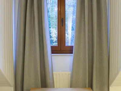 a window with curtains next to a wooden table at Retreat near Maasmechelen in Lanaken