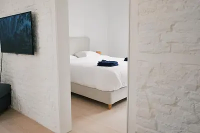 a white bedroom with a bed and a mirror at Urbanchic Appart lumineux hyper centre in Liège