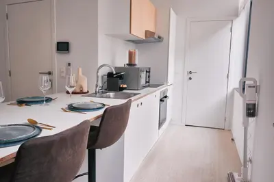 a white kitchen with a table and chairs at Urbanchic Appart lumineux hyper centre in Liège