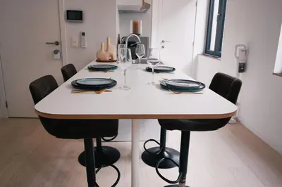 a dining room table with black chairs and a white table at Urbanchic Appart lumineux hyper centre in Liège