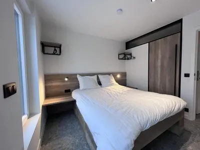 a bedroom with a large white bed with a wooden headboard at Bigaro II in Heers
