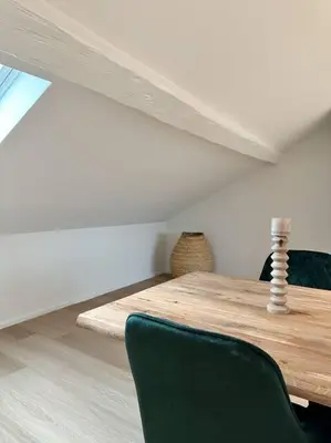a dining room with a wooden table and a green chair at Duplex hyper centre in Liège