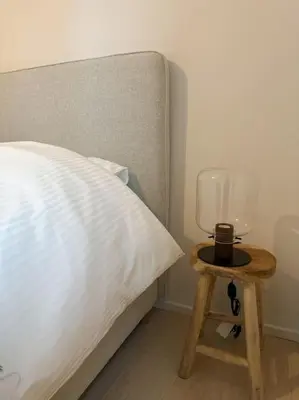 a bed with a table next to a bed with a lamp on it at Duplex hyper centre in Liège