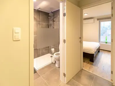 a bathroom with a toilet and a bed in a room at Maasmechelen Duplex Retreat in Maasmechelen