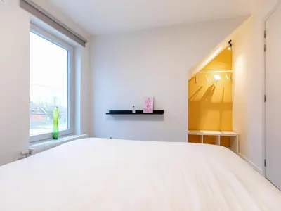 a bedroom with a white bed and a window at Maasmechelen Duplex Retreat in Maasmechelen