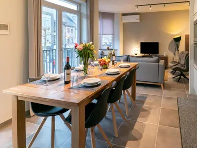 a dining room table with chairs and a couch at Maasmechelen Duplex Retreat in Maasmechelen