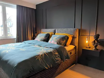 a bedroom with a bed with a blue comforter and a window at Red cross street in Lommel