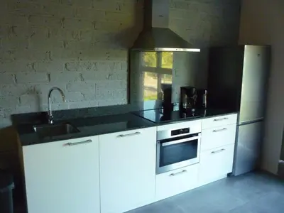 a kitchen with white cabinets and a black counter top at De Hoog Velden 15 in Overpelt