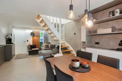a kitchen and living room with a table and a staircase at Bos-Chalet bij Wijers Wandelroutes, Rust & Gezinsplezier Fijnspar 108 Hengelhoef in Houthalen-Helchteren