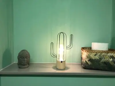 a candle on a shelf with a statue and a cactus at Casa Sandra Elisa in Maasmechelen