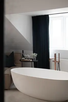 a white tub in a room with a couch and a window at MAM Haspengouw in Sint-Truiden