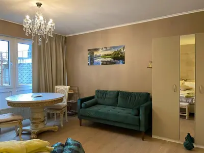 a living room with a green couch and a table at Studio Montaigne in Liège