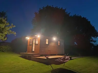 a small wooden house with a boat in the grass at La roulotte de Soiron in Pepinster