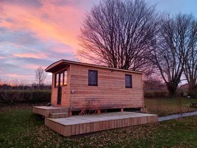 a tiny house in a field with a sunset at La roulotte de Soiron in Pepinster