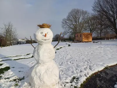 a snowman is sitting in the snow at La roulotte de Soiron in Pepinster