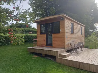 a small wooden cabin with a table and chairs on a deck at La roulotte de Soiron in Pepinster
