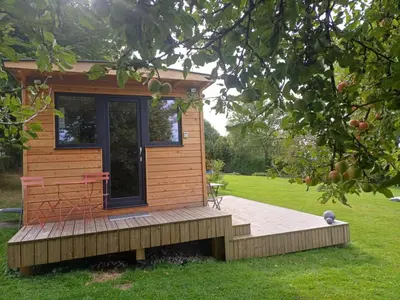 a tiny house with a deck in the grass at La roulotte de Soiron in Pepinster