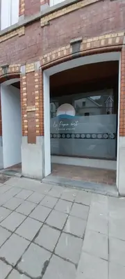 two garage doors in a brick building with a store window at Le Pepin Dort in Pepinster