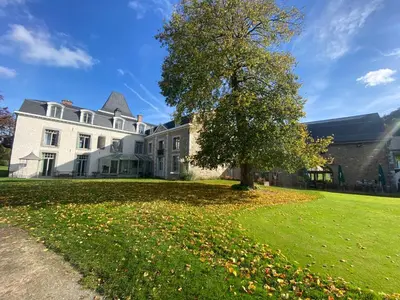 a large white house with a tree in the yard at La chambre et le studio du château du golf de Bernalmont in Liège