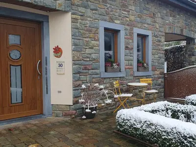 a stone house with a door and a table and chairs at Studio Klimt Eupen in Eupen