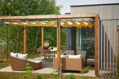 a pergola with chairs and tables on a patio at Terhills Resort by Center Parcs in Dilsen-Stokkem