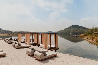a row of lounge chairs on the shore of a lake at Terhills Resort by Center Parcs in Dilsen-Stokkem