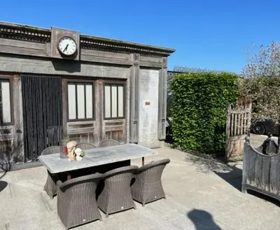 a table and chairs in front of a building with a clock at B&B Els in Locht