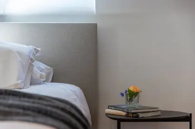 a bed with a side table with books and a vase of flowers at Ca'Triz in Borgloon