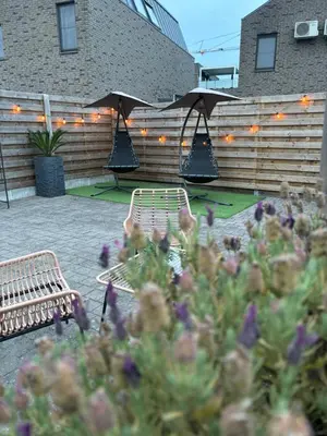 a patio with benches and flowers and lights at Guesthouse 66 in Lommel