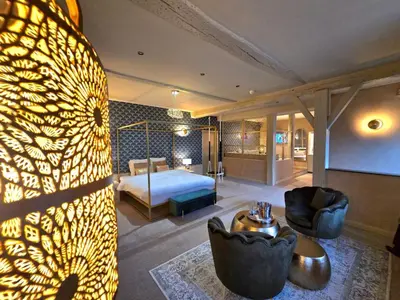 a hotel room with a bed and a living room at Le Clos des Thermes in Chaudfontaine