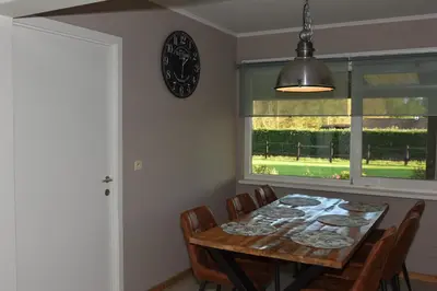 a dining room table with chairs and a clock on the wall at Kiefhoekhuisje in Hechtel-Eksel