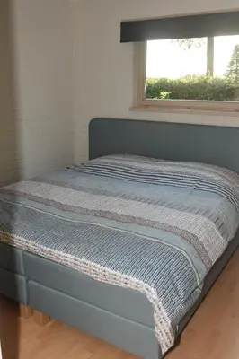 a bed in a room with a window at Kiefhoekhuisje in Hechtel-Eksel