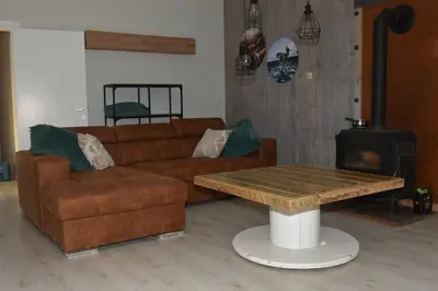 a living room with a couch and a table and a stove at Kiefhoekhuisje in Hechtel-Eksel