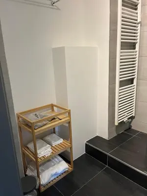 a bathroom with a shelf with towels and a window at Cosy Louvrex -Liège Francorchamps in Liège
