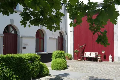a red and white building with a bench in front of it at Domein Tombos in Gingelom