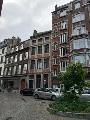 a large brick building with cars parked in front of it at Logment saint denis in Liège