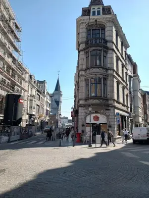 a tall building on a city street with people walking at Logment saint denis in Liège
