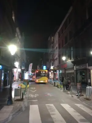 a yellow bus driving down a city street at night at Logment saint denis in Liège
