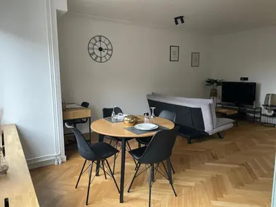 a living room with a table and chairs and a television at L’émeraude in Liège