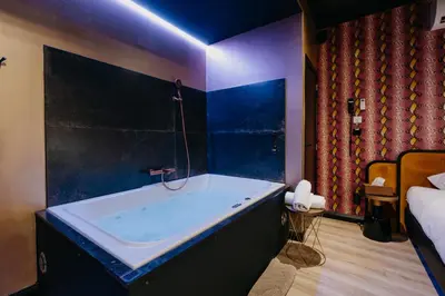 a bathroom with a bath tub in a bedroom at Hôtel Mademoiselle in Liège