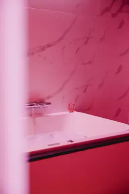 a pink bathroom with a tub and a red wall at Hôtel Mademoiselle in Liège