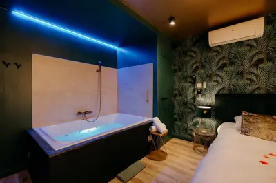 a bathroom with a bath tub next to a bed at Hôtel Mademoiselle in Liège