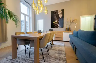 a dining room with a table and a couch at The 99, Appartement sauna & parking in Liège