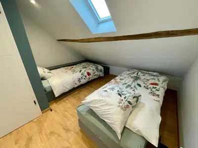 a attic bedroom with two beds and a window at Gite de Clermont in Thimister