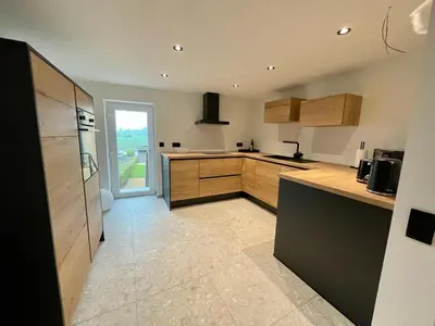 a kitchen with wooden cabinets and a large appliance at Gite de Clermont in Thimister