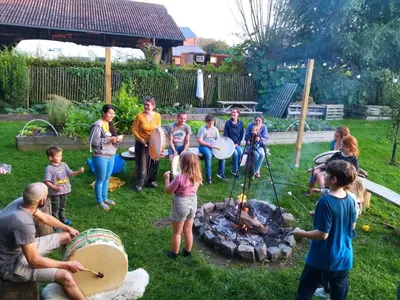 a group of people standing around a fire in a yard at Belevingshoeve 